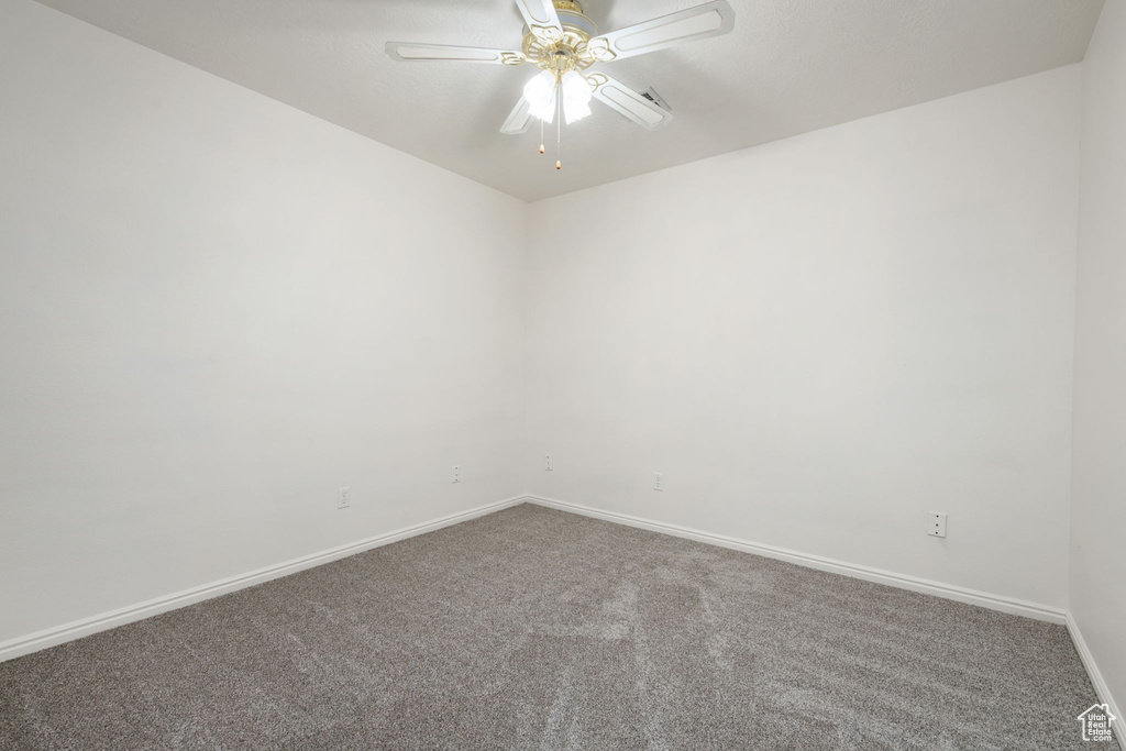 Unfurnished room featuring carpet floors, a ceiling fan, and baseboards