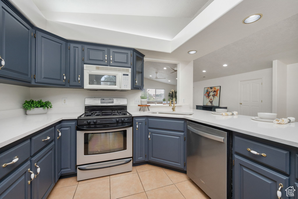 Kitchen featuring light countertops, blue cabinetry, light tile patterned flooring, and stainless steel appliances