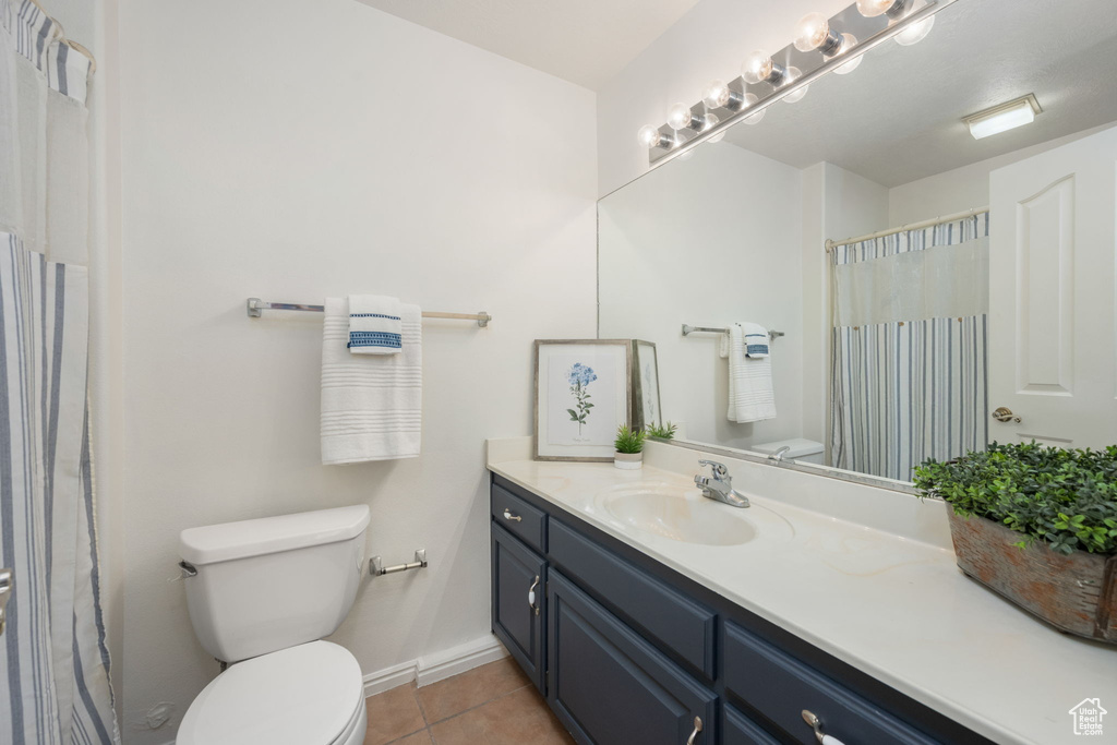 Bathroom with vanity, baseboards, tile patterned floors, and toilet