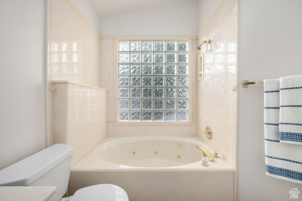Full bathroom with a jetted tub, toilet, a shower, and lofted ceiling
