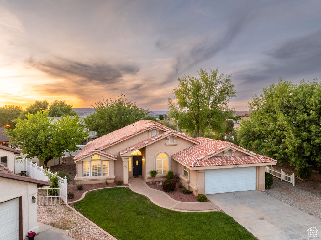Mediterranean / spanish-style house with fence, concrete driveway, stucco siding, and an attached garage