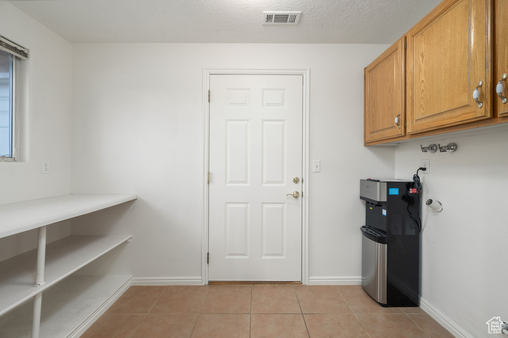 Laundry area with baseboards, visible vents, and light tile patterned floors