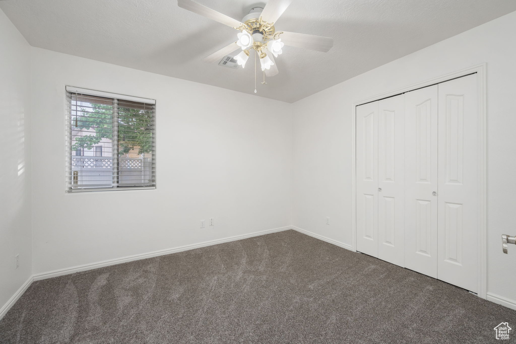 Unfurnished bedroom featuring dark colored carpet, baseboards, and a closet