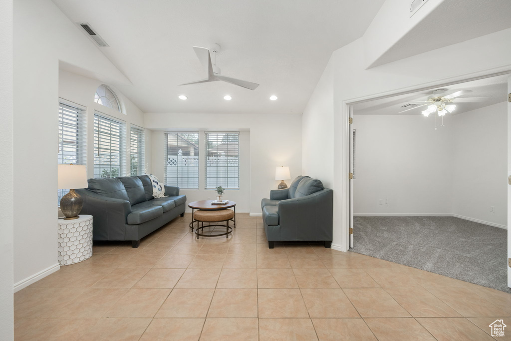 Living area featuring light tile patterned flooring, ceiling fan, and vaulted ceiling