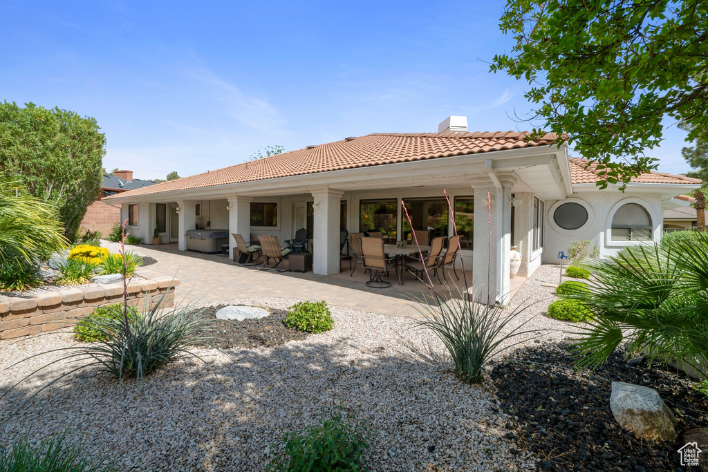 Back of property featuring a patio, a chimney, stucco siding, and a tile roof