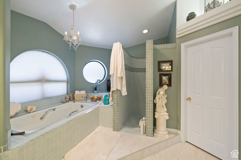 Full bath featuring a garden tub, marble finish floor, lofted ceiling, a walk in shower, and a notable chandelier