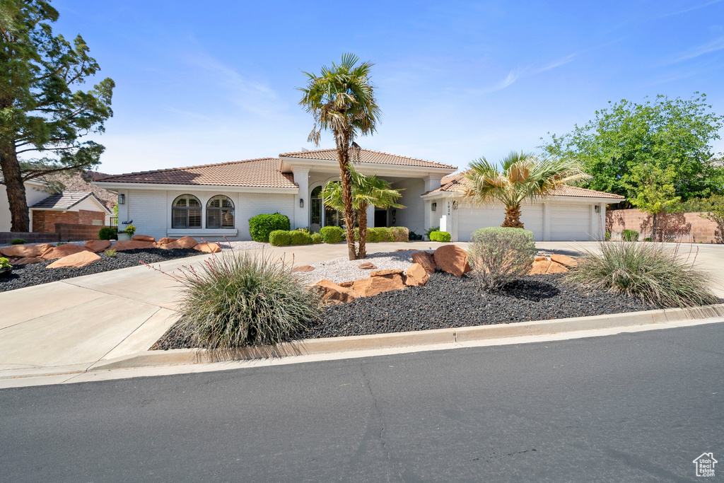 View of front of property with an attached garage, stucco siding, a tile roof, and concrete driveway