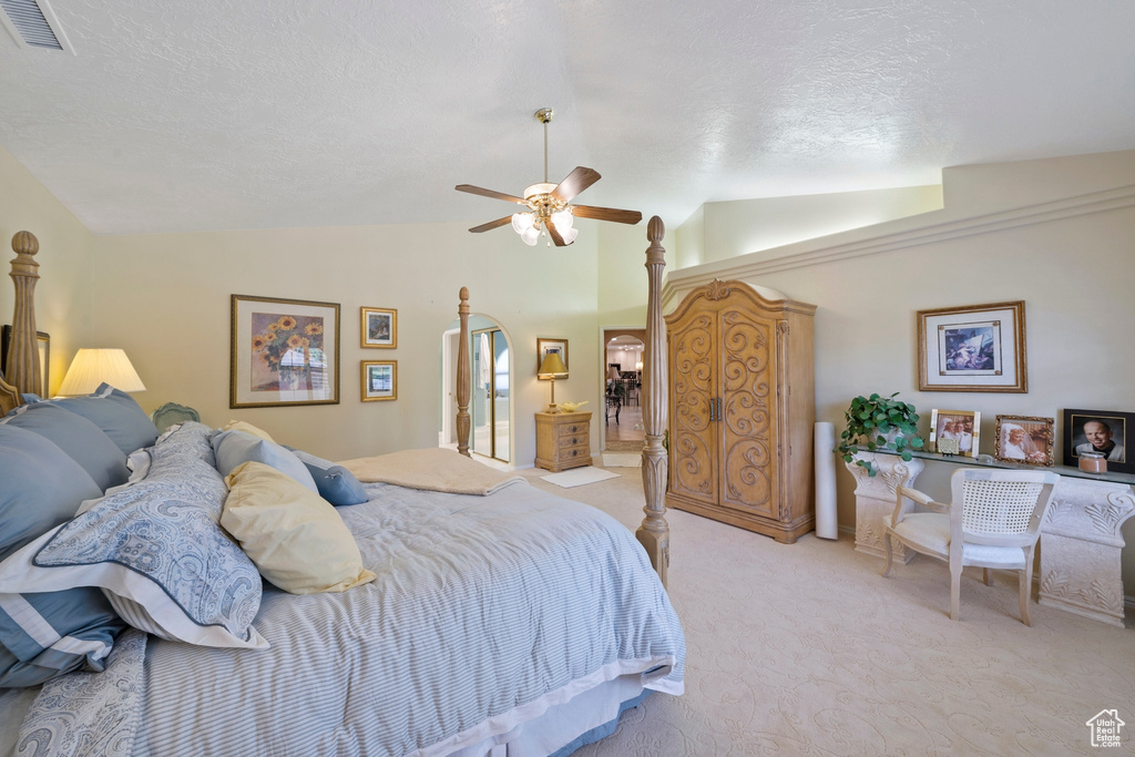 Bedroom featuring a ceiling fan, a textured ceiling, visible vents, vaulted ceiling, and light carpet