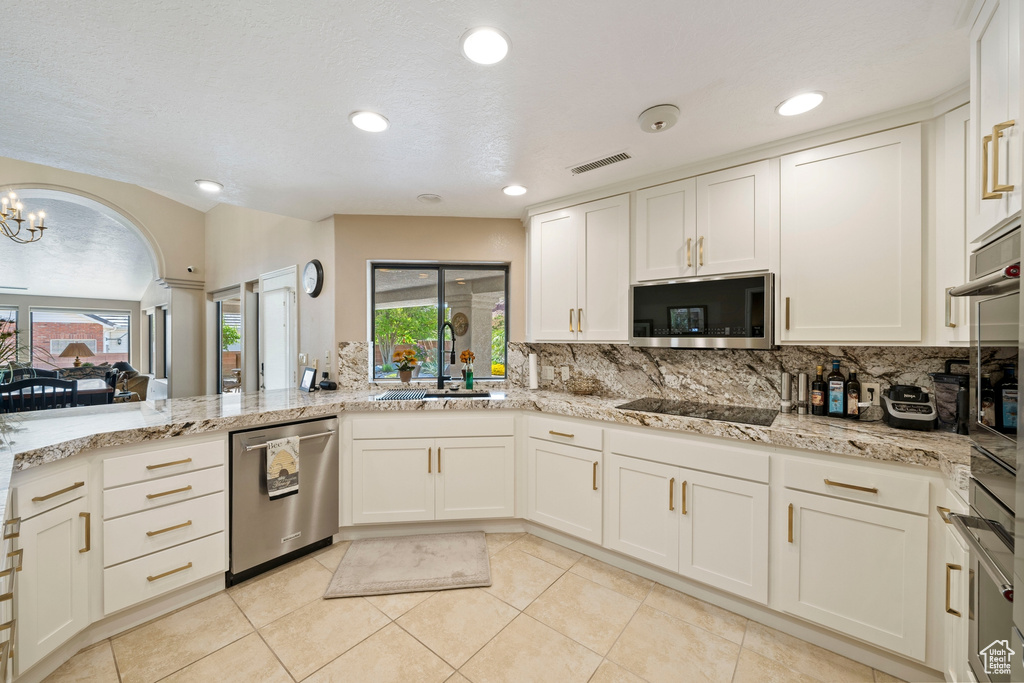 Kitchen featuring a sink, backsplash, light tile patterned flooring, and stainless steel appliances