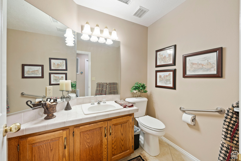 Bathroom with visible vents, vanity, toilet, baseboards, and tile patterned floors