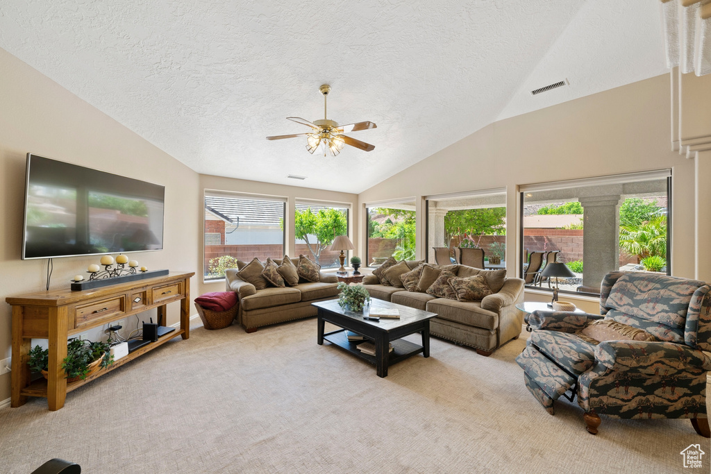 Carpeted living room featuring a textured ceiling, ceiling fan, visible vents, and lofted ceiling