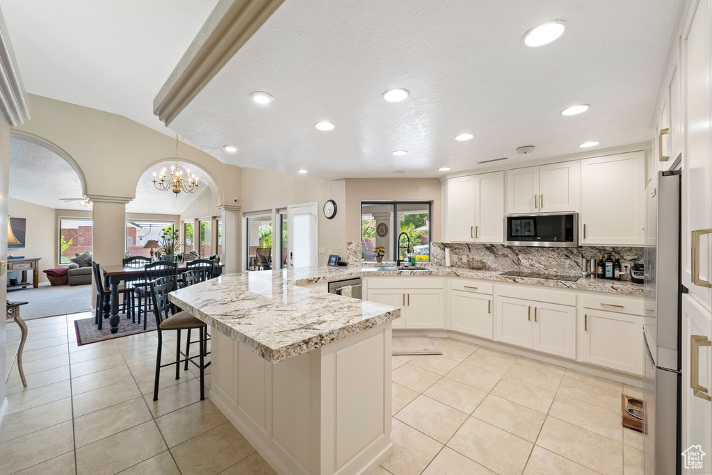 Kitchen featuring stainless steel appliances, ornate columns, a sink, and a healthy amount of sunlight