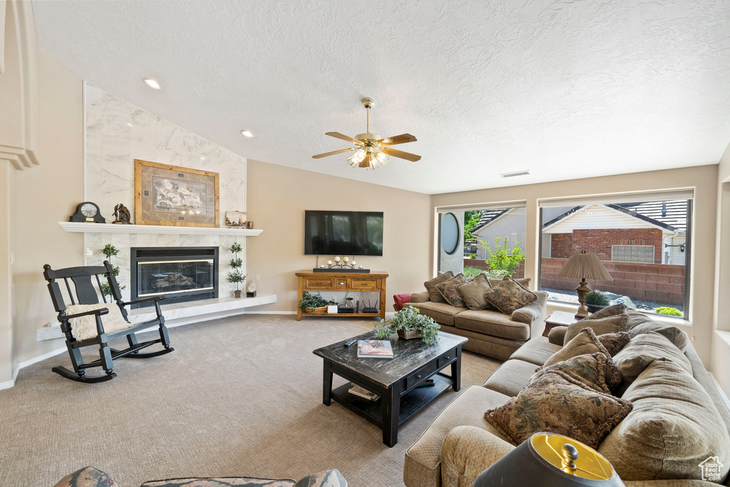 Carpeted living area with a textured ceiling, vaulted ceiling, ceiling fan, and visible vents