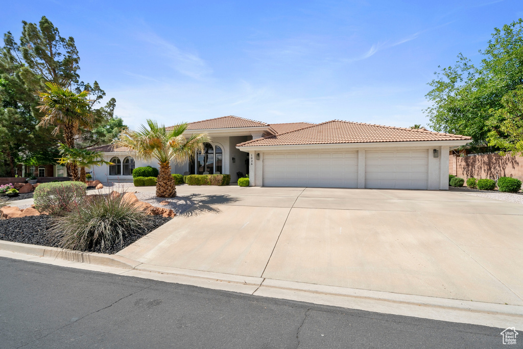 View of front of house featuring a garage, stucco siding, a tiled roof, and driveway