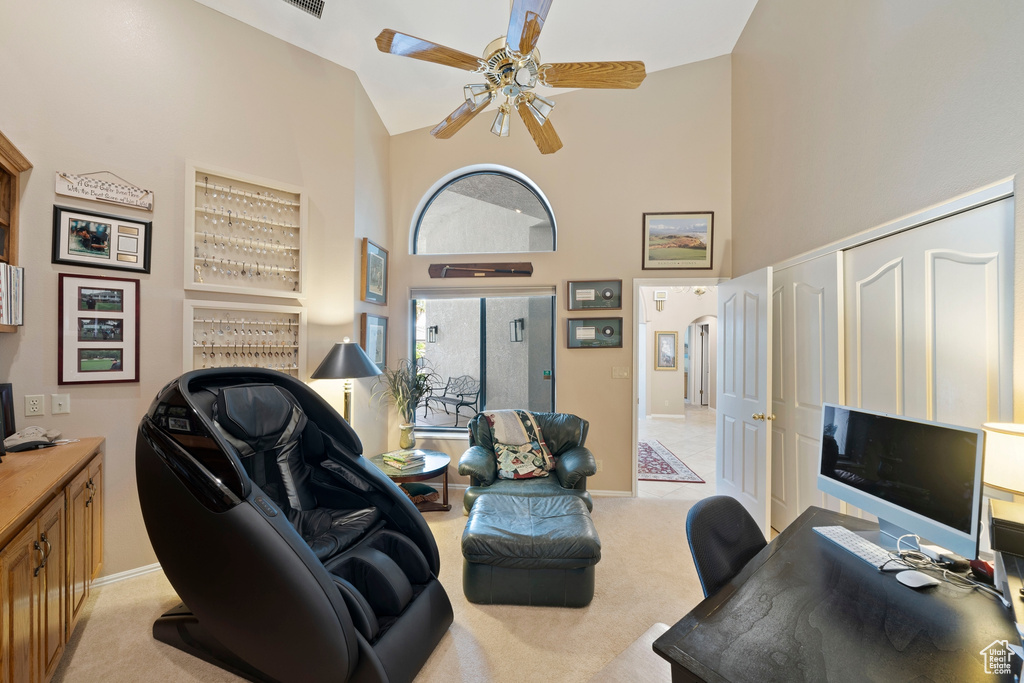 Home office with high vaulted ceiling, baseboards, a ceiling fan, and light colored carpet