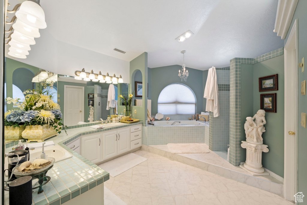 Full bath featuring a notable chandelier, vanity, marble finish floor, visible vents, and a garden tub
