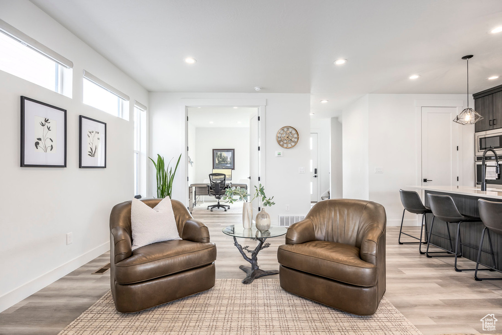 Living area with recessed lighting, light wood finished floors, baseboards, and visible vents