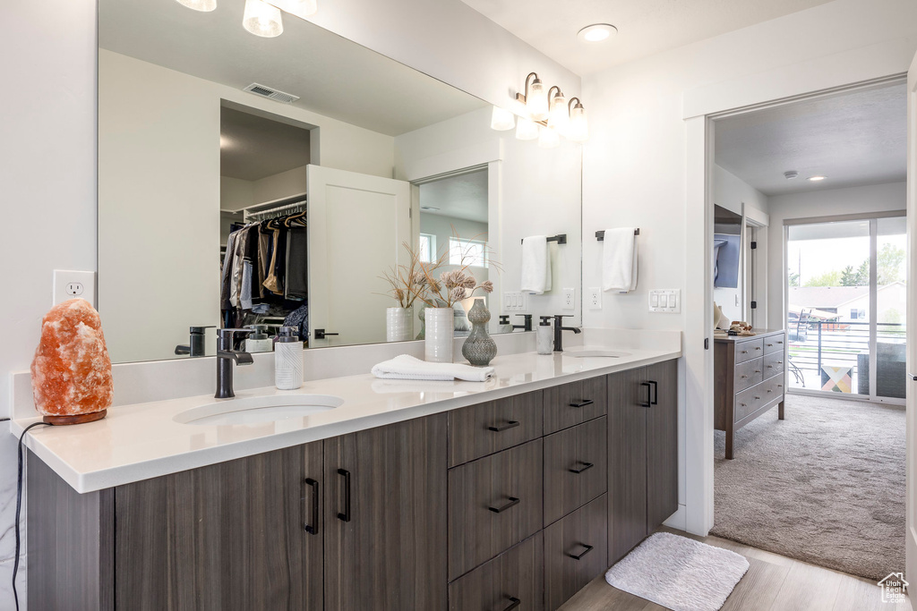 Bathroom with double vanity, visible vents, a sink, and wood finished floors