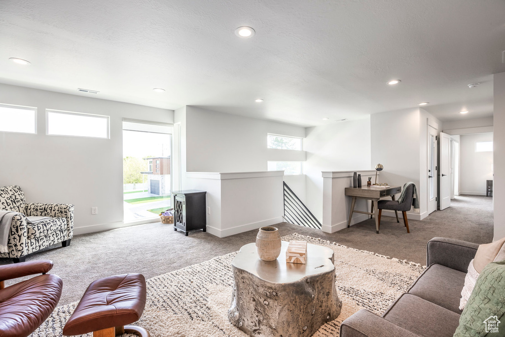 Carpeted living area with recessed lighting, baseboards, and visible vents