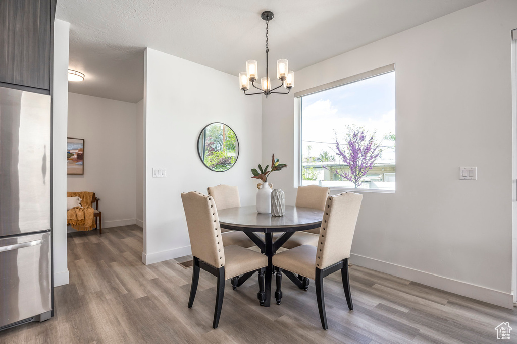 Dining area with baseboards, an inviting chandelier, and light wood-style floors