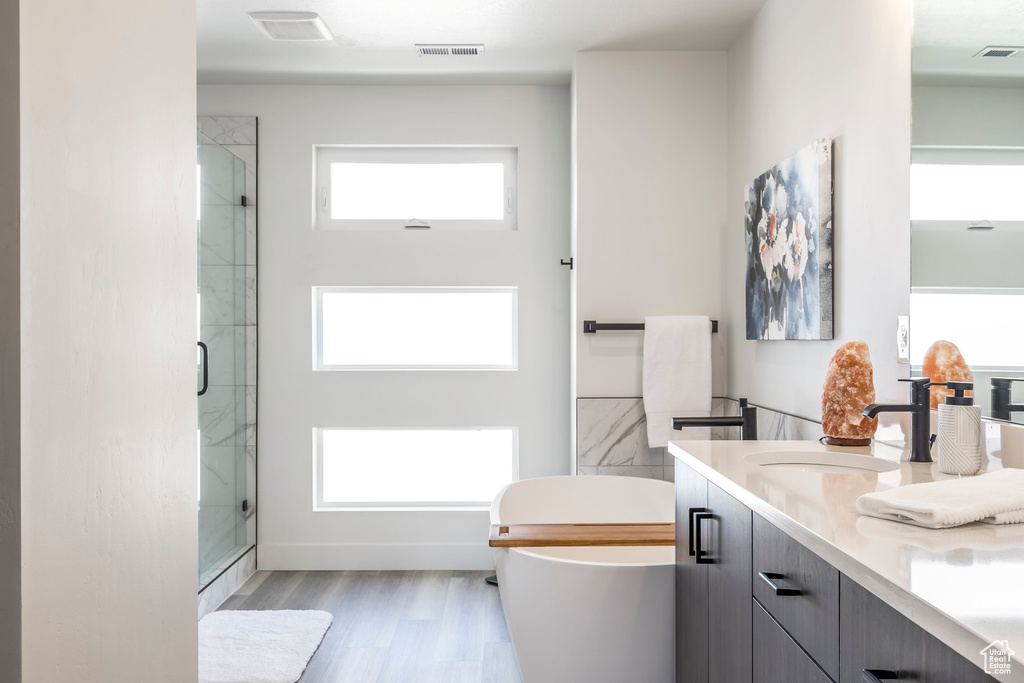 Full bath with double vanity, visible vents, a stall shower, a sink, and a soaking tub