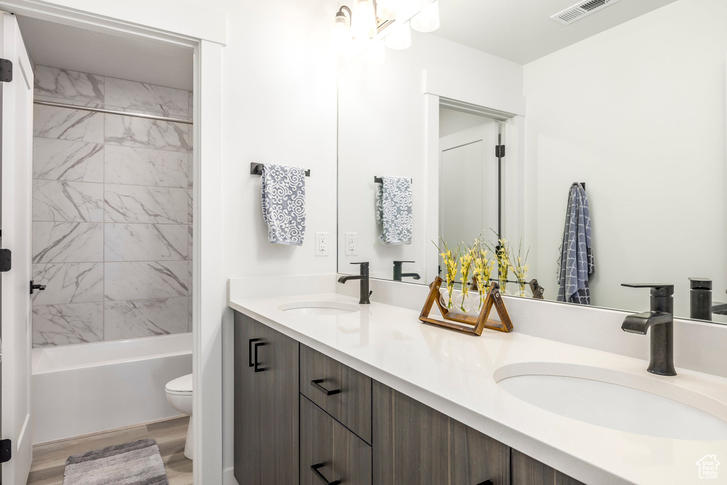 Full bath with a sink, toilet, double vanity, and visible vents