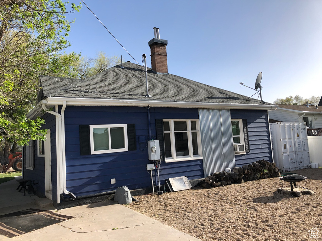 Back of property with roof with shingles and a chimney