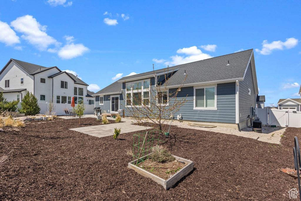 Back of property featuring fence, a vegetable garden, a gate, cooling unit, and a patio