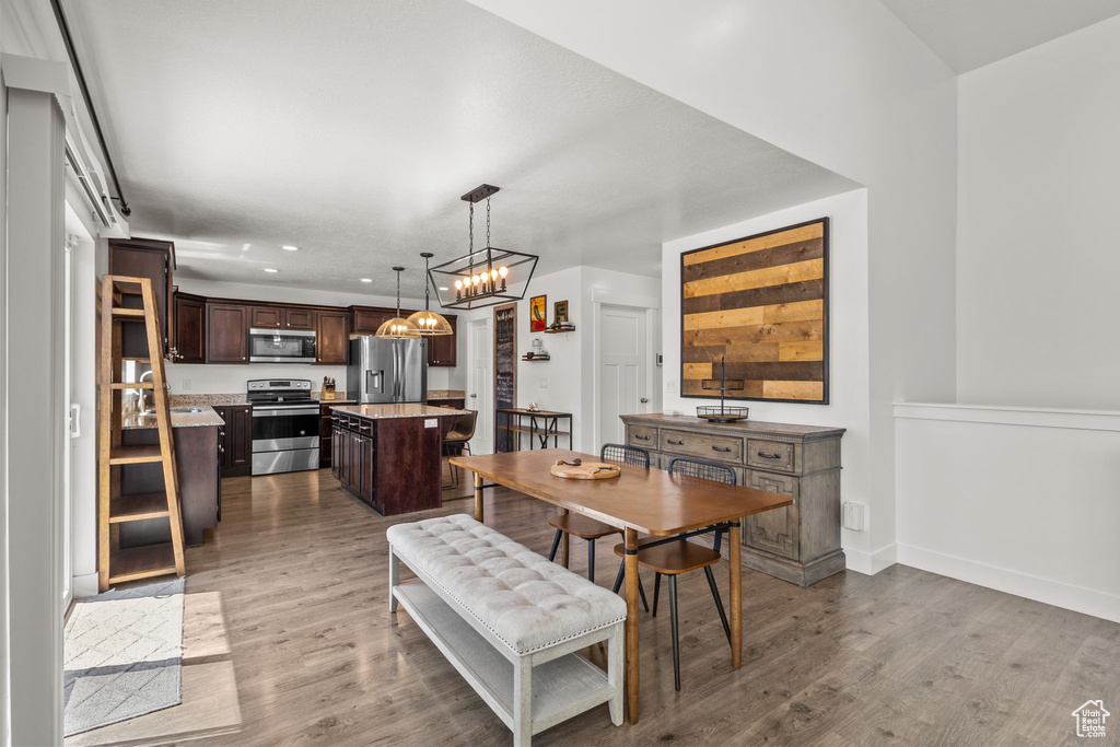 Dining space featuring dark wood-style flooring, baseboards, a notable chandelier, and recessed lighting