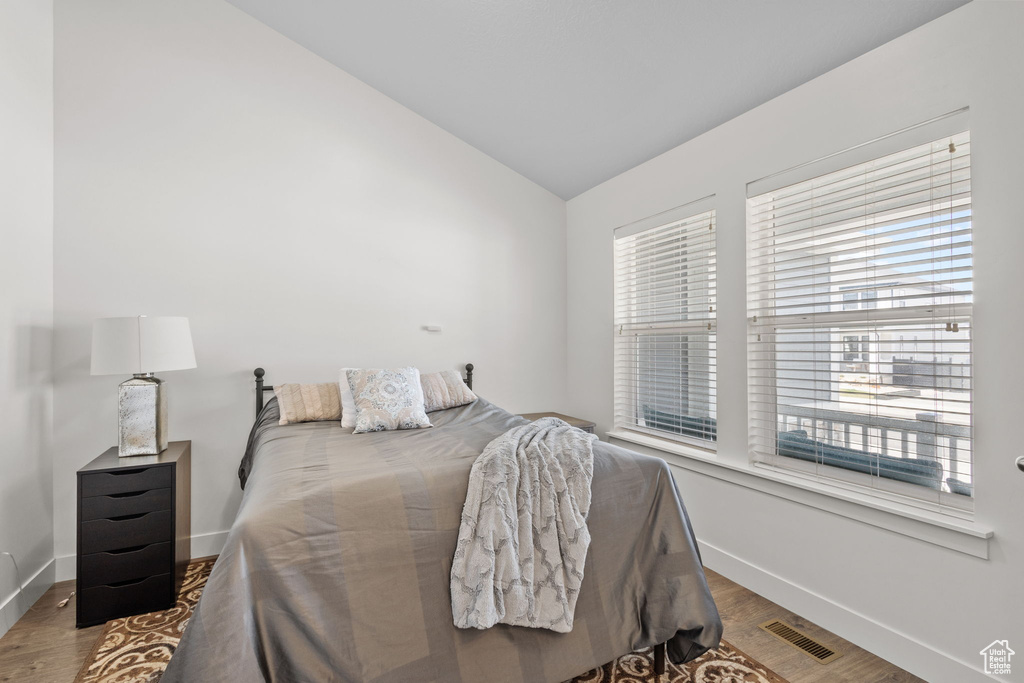 Bedroom featuring visible vents, baseboards, lofted ceiling, and wood finished floors