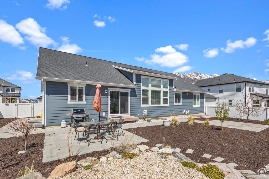 Back of house featuring a gate, a patio area, fence, and a shingled roof
