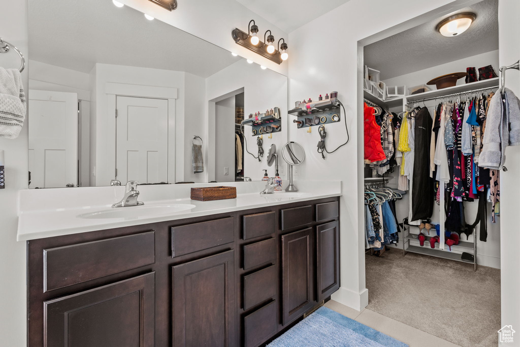 Bathroom with double vanity, a sink, tile patterned floors, and a spacious closet