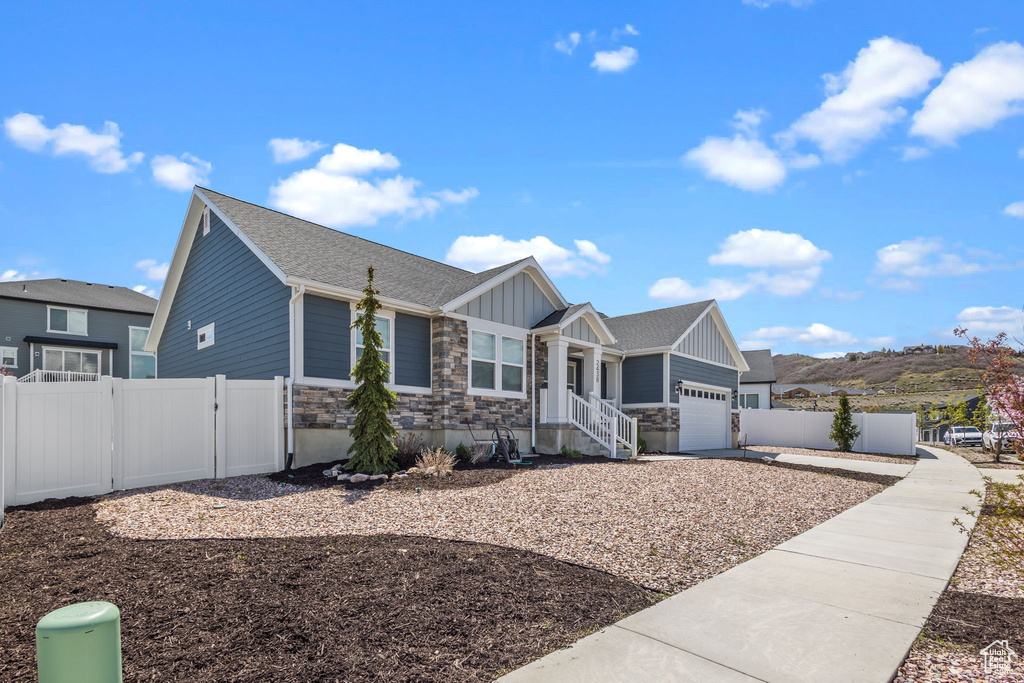 Single story home with fence, board and batten siding, an attached garage, and stone siding