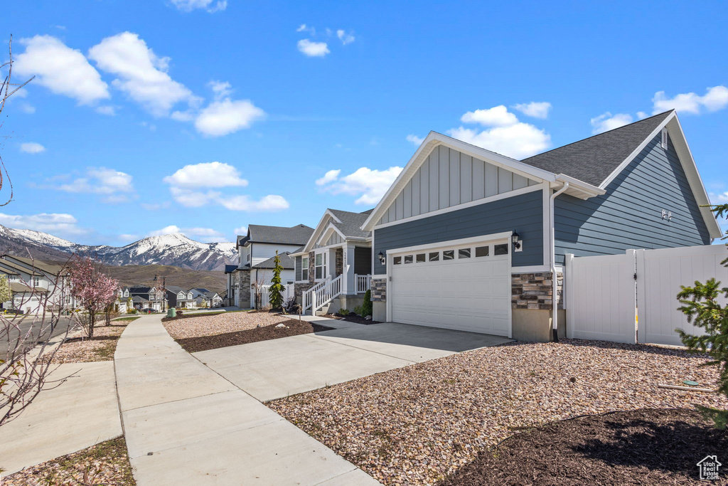 View of front of house with fence, stone siding, board and batten siding, concrete driveway, and an attached garage