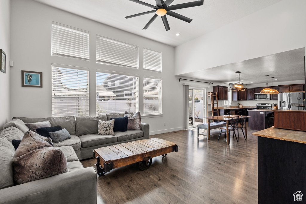 Living room featuring a towering ceiling, baseboards, dark wood-style floors, recessed lighting, and a ceiling fan