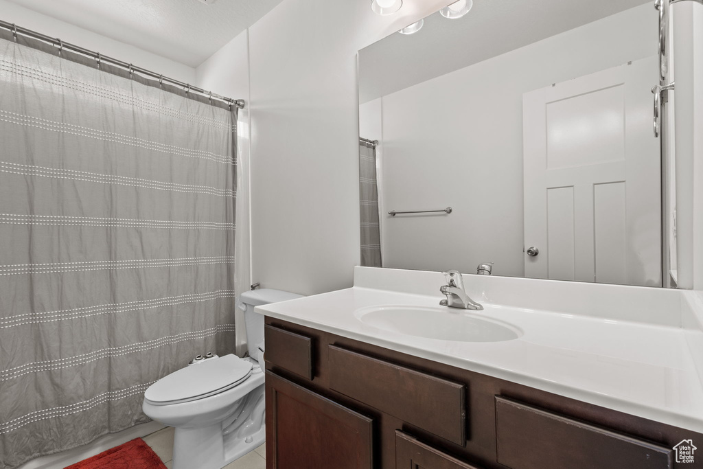 Full bath featuring vanity, tile patterned floors, and toilet