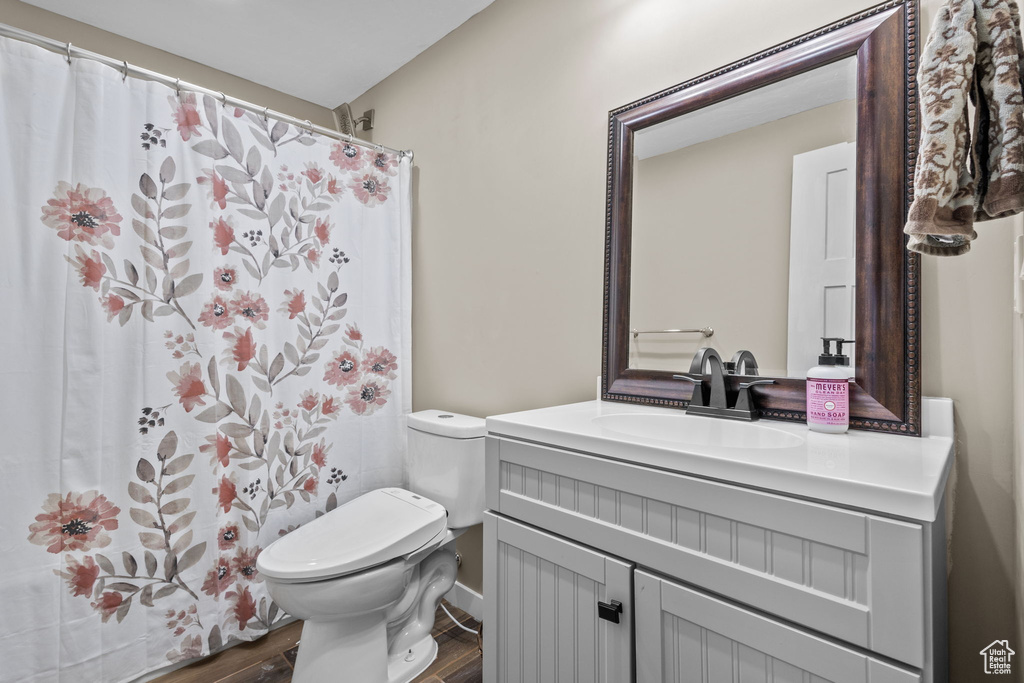 Full bath with a shower with shower curtain, toilet, wood finished floors, and vanity