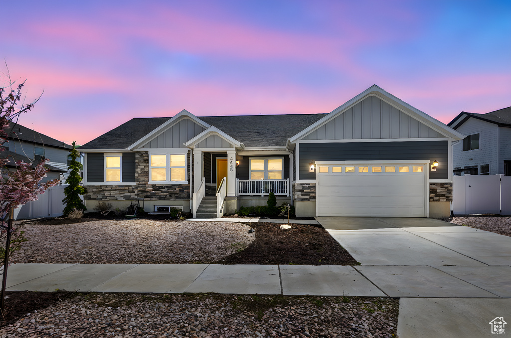 View of front of house with a garage, fence, board and batten siding, concrete driveway, and a porch