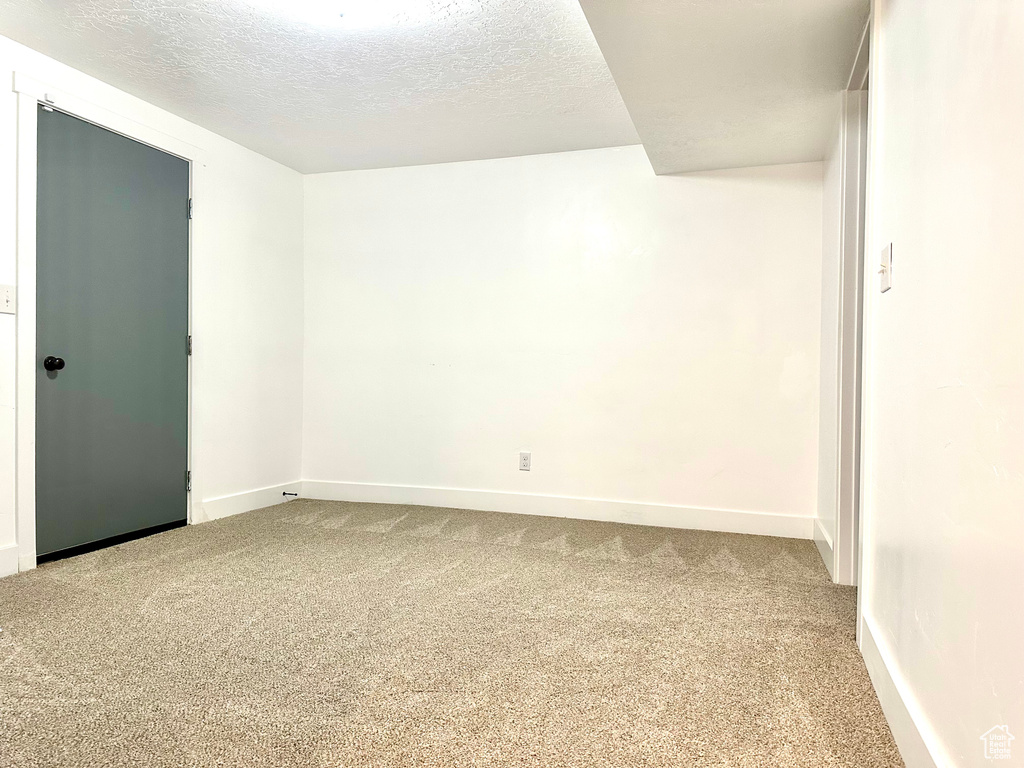 Unfurnished room featuring baseboards, carpet flooring, and a textured ceiling