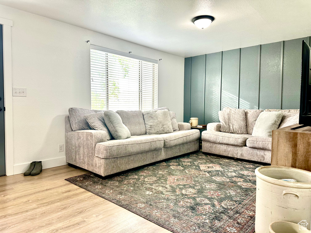 Living area with baseboards, a textured ceiling, and wood finished floors