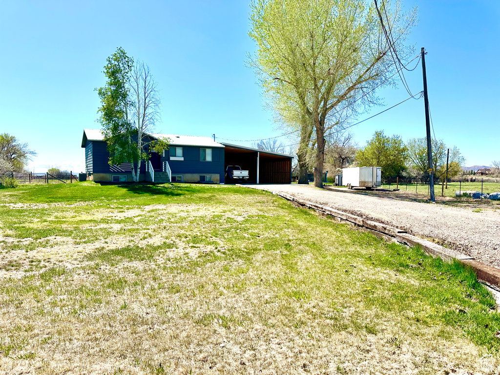 View of front of property featuring fence, driveway, a front yard, and a carport