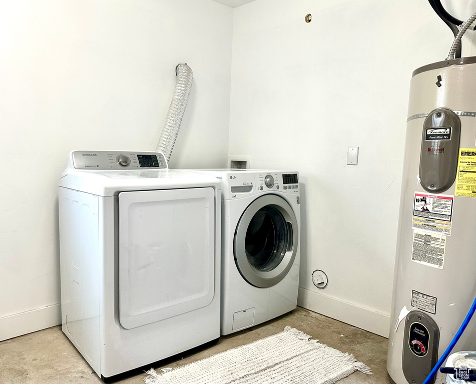 Clothes washing area with laundry area, baseboards, water heater, and washing machine and dryer