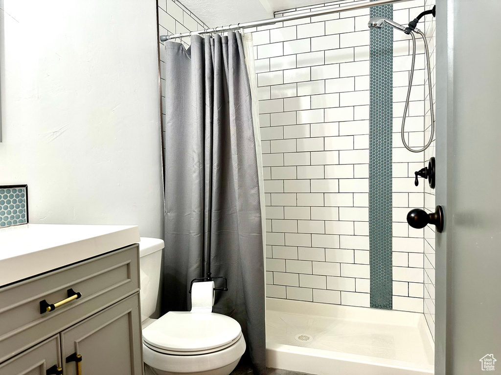 Bathroom featuring vanity, toilet, and a shower stall
