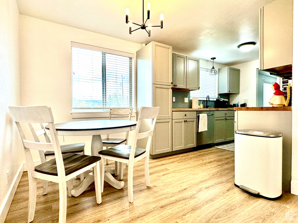Kitchen with an inviting chandelier, light wood-type flooring, a sink, dishwasher, and hanging light fixtures