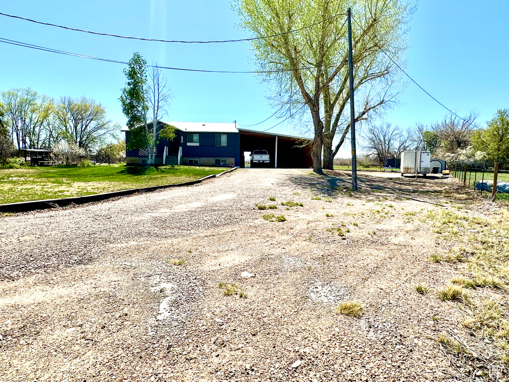 View of front of property featuring driveway, an outbuilding, and a carport