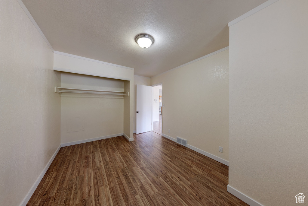 Unfurnished bedroom with baseboards, a closet, wood finished floors, and visible vents