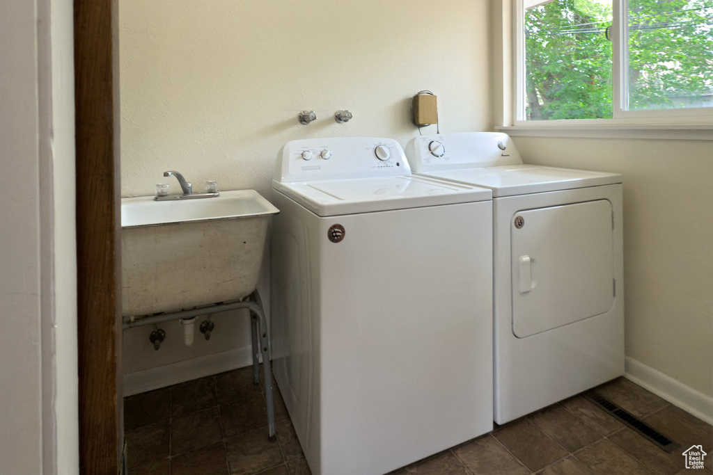 Clothes washing area featuring laundry area, visible vents, washing machine and clothes dryer, a sink, and baseboards