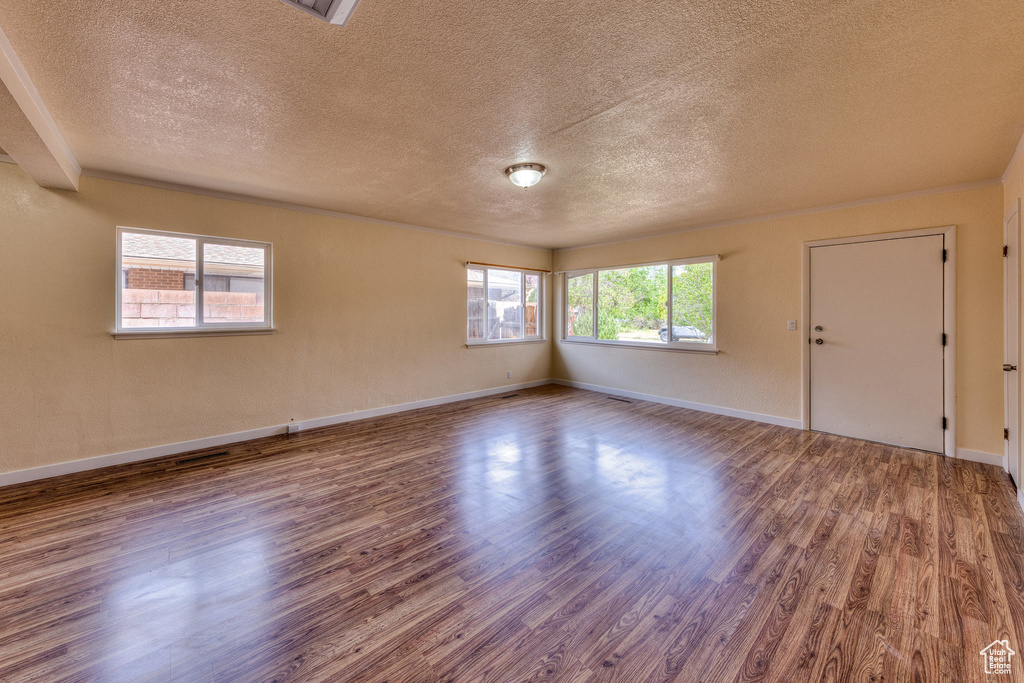 Spare room featuring baseboards, a textured ceiling, and wood finished floors