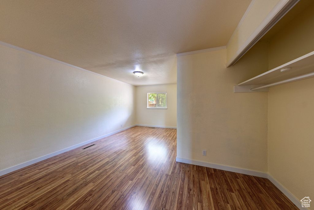 Additional living space featuring visible vents, baseboards, and wood finished floors