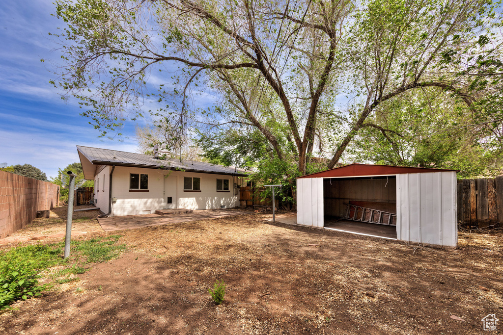 Back of house featuring an outdoor structure, a fenced backyard, and metal roof